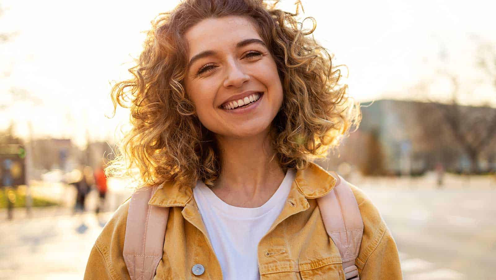 a woman smiling with a backpack - Marion Cosmetic Dentist