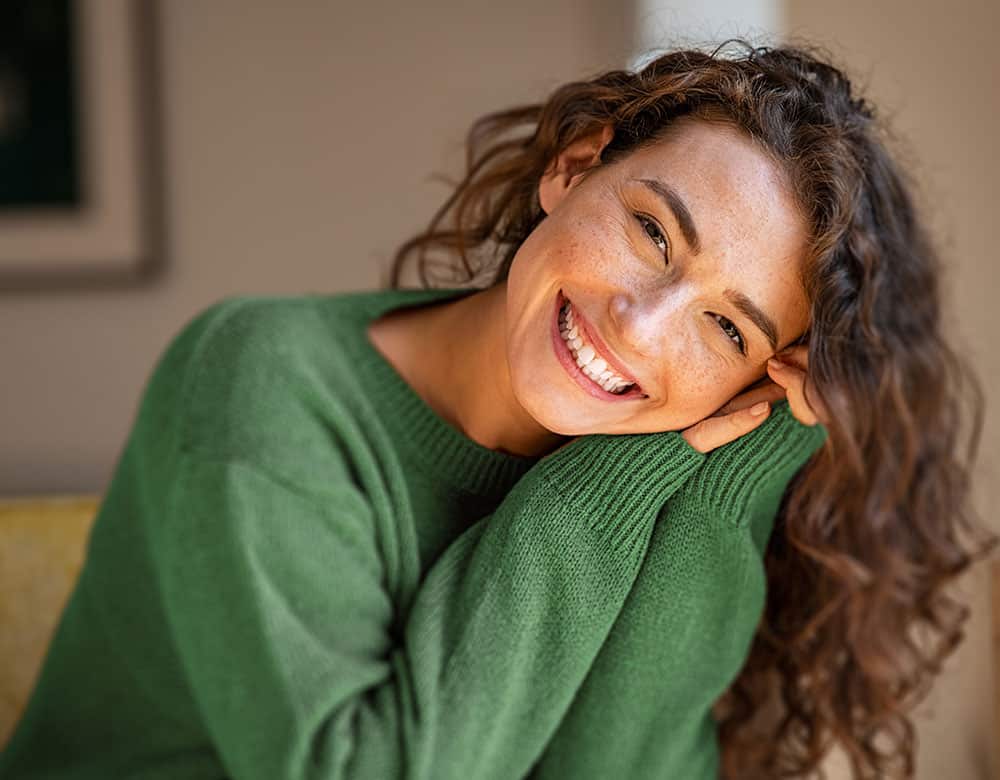 a woman smiling with her hands on her head