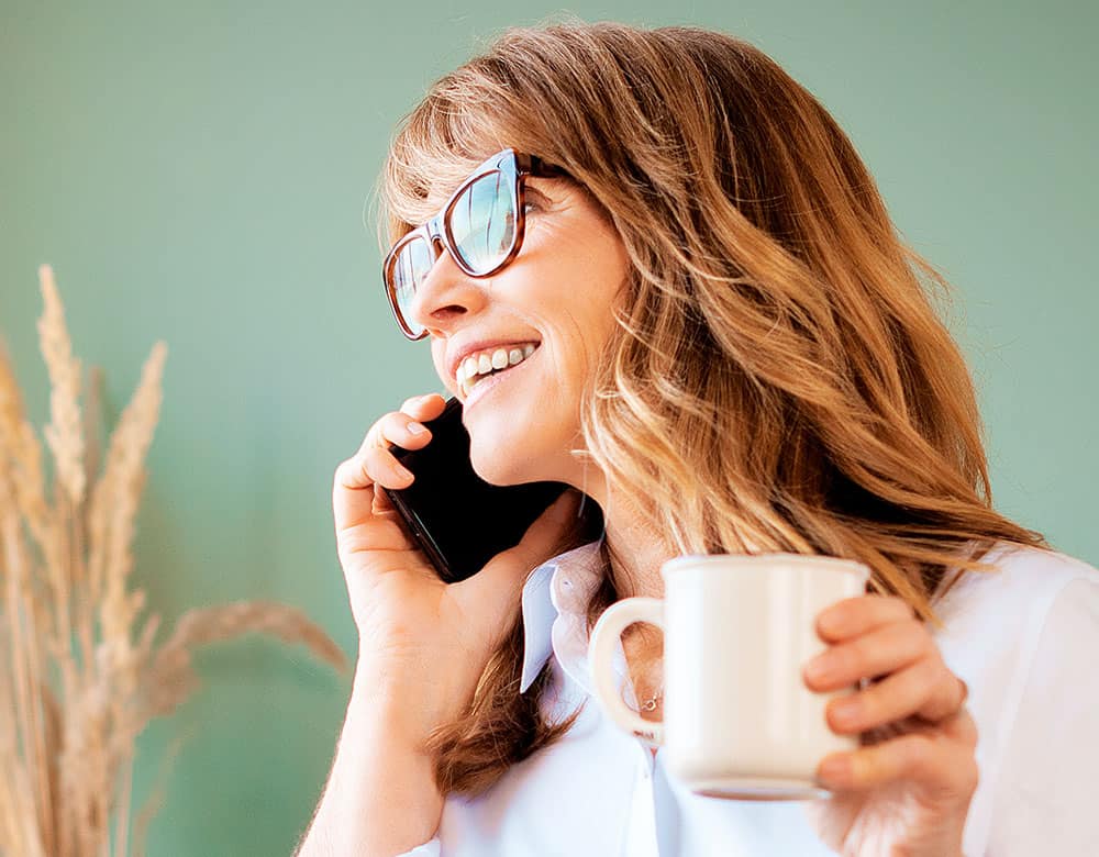 a woman holding a coffee cup and talking on a phone