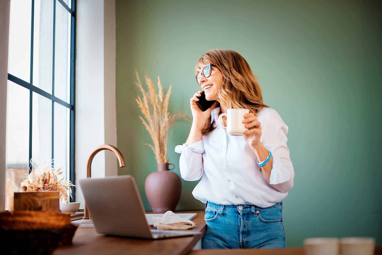 a woman holding a cup and talking on a phone