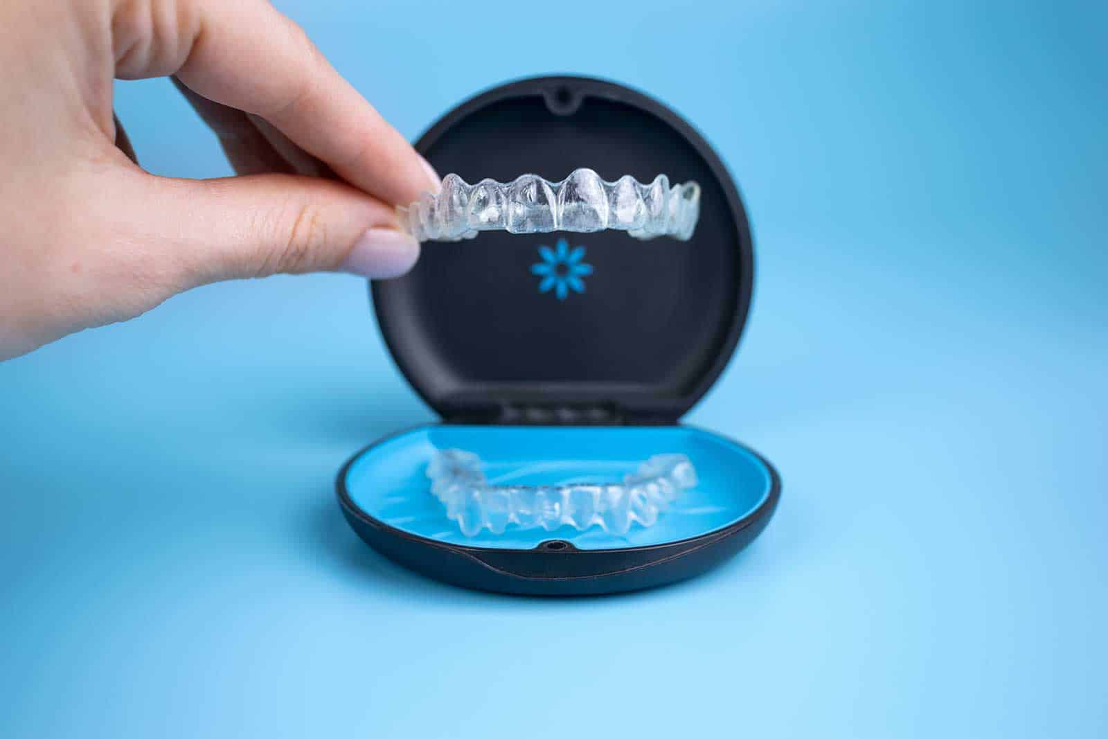 a hand holding an invisalign clear aligner